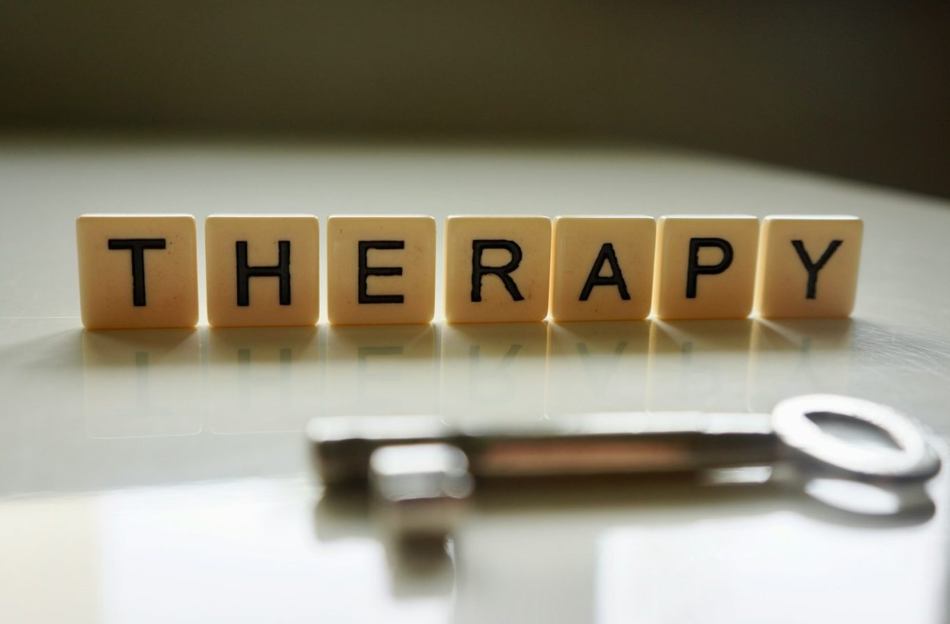 Psychothérapie Lettres en bois formant le mot "THERAPY" avec une clé en métal à côté.